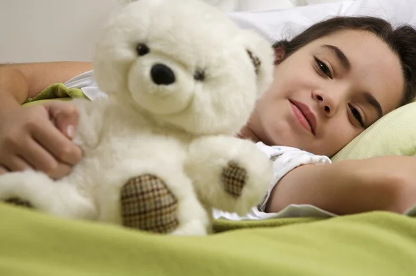 Niña acostada en la cama con oso — Foto de Stock