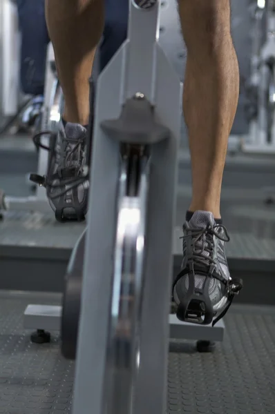 male legs on pedals of stationary bicycle