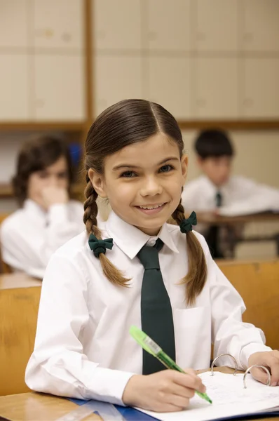 Colegiala escribiendo en libro de ejercicios — Foto de Stock