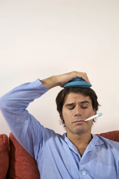 Hombre con termómetro en la boca y calentador en la cabeza — Foto de Stock