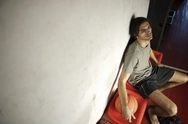 Basketball player sitting in gym hall — Stock Photo, Image