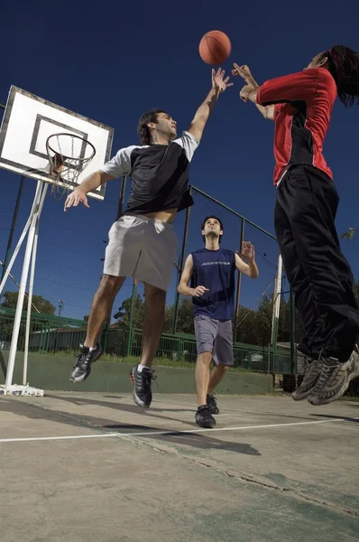 Three young men playing basketball
