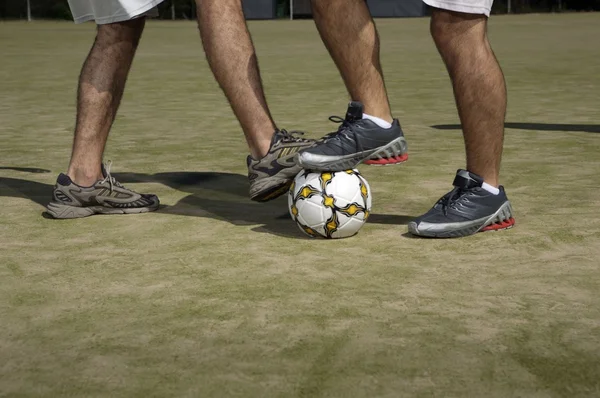 Мужские ноги играют в футбол — стоковое фото