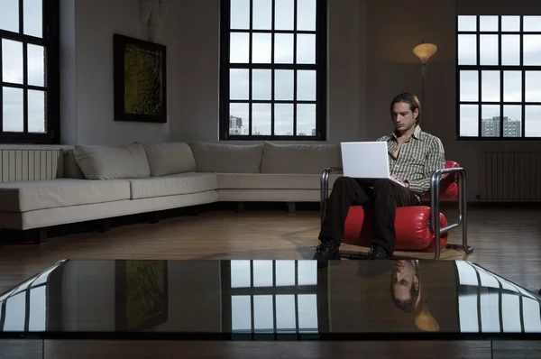 Genç adam dizüstü bilgisayarla oturuyor. — Stok fotoğraf
