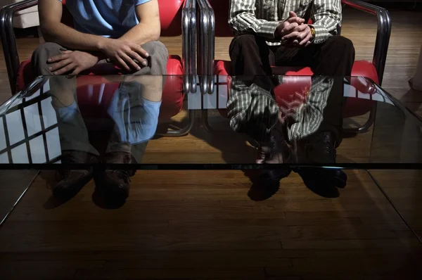 Homens em cadeiras com reflexão sobre a mesa — Fotografia de Stock