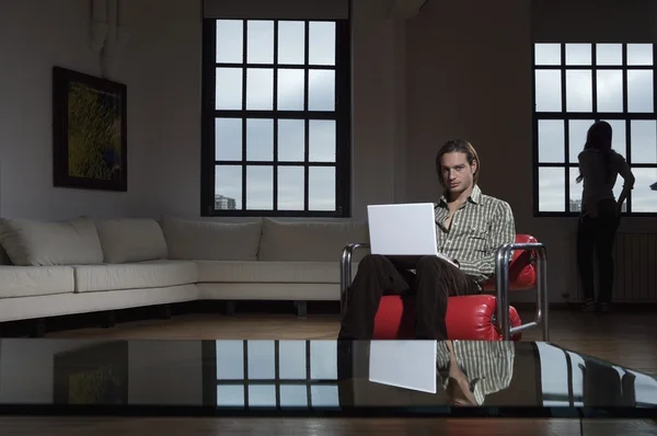 Genç adam dizüstü bilgisayarla oturuyor. — Stok fotoğraf