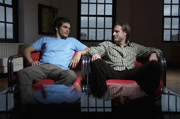 Friends sitting in red armchairs — Stock Photo, Image