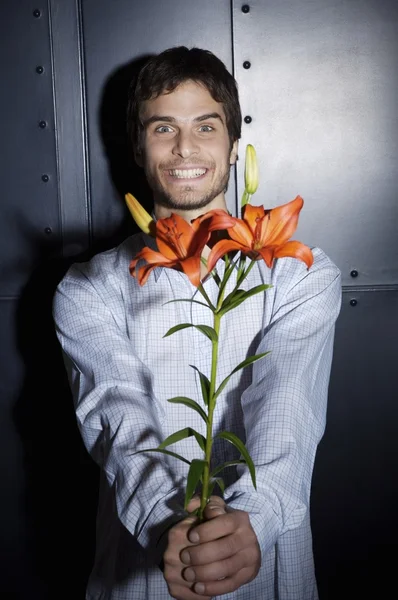 Hombre joven sosteniendo flores de lirio — Foto de Stock