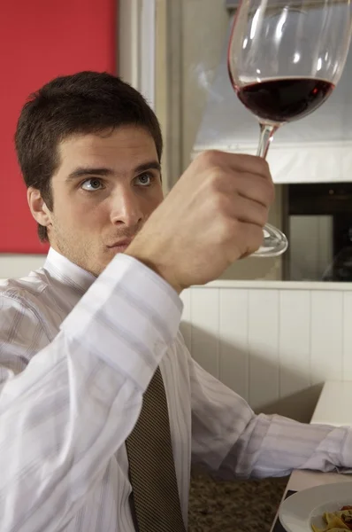 Il giovane guarda il bicchiere di vino — Foto Stock