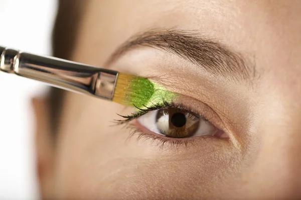 Mujer aplica sombra de ojos con un cepillo — Foto de Stock