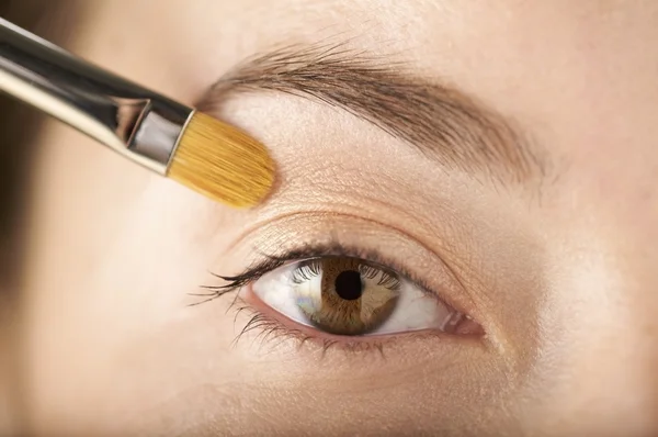 Mujer aplica sombra de ojos con un cepillo — Foto de Stock