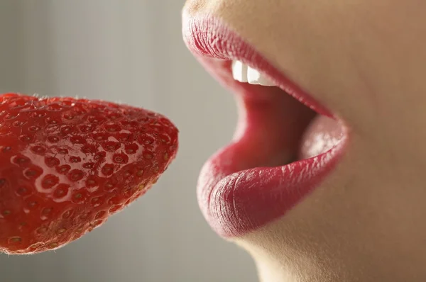 Female mouth eating strawberry Royalty Free Stock Photos