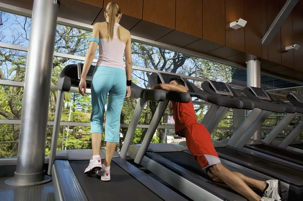 Mujer y hombre haciendo ejercicio en una cinta de correr — Foto de Stock