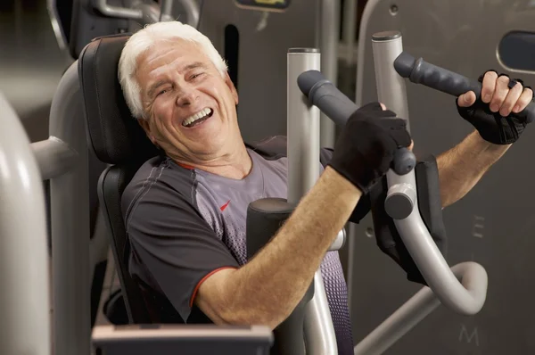Hombre haciendo ejercicio con máquinas de peso — Foto de Stock