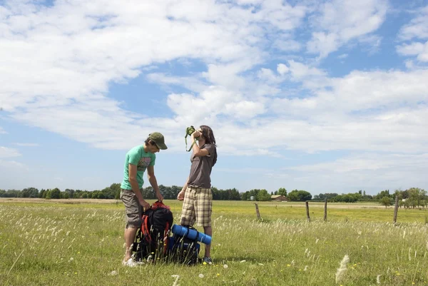 Backpackers wody pitnej na łące — Zdjęcie stockowe