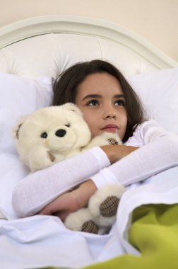 küçük kız yatakta ayı sarılma