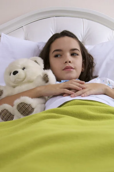 Маленькая девочка лежит в постели с медведем — стоковое фото