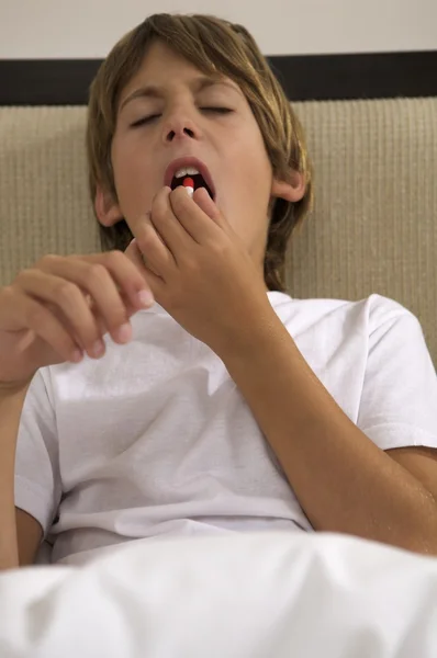 Pequeño niño poniendo píldora en la boca — Foto de Stock