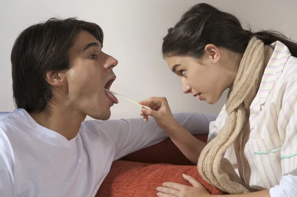 Woman looking down man 's throat — стоковое фото