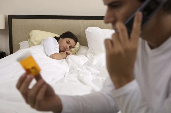 Hombre hablando por teléfono y mirando píldoras — Foto de Stock