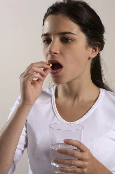 Mulher colocando pílula na boca — Fotografia de Stock