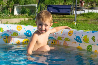 Bir çocuk bir şişme havuzda yüzüyor