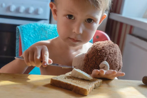 Мальчик кладёт сыр на тост — стоковое фото
