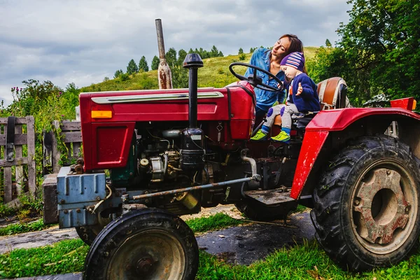Мать и сын сидят на тракторе Лицензионные Стоковые Изображения