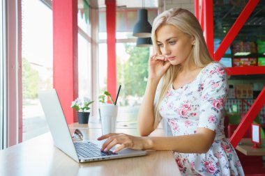 Bir dizüstü bilgisayar bir kafede çalışan genç kız.