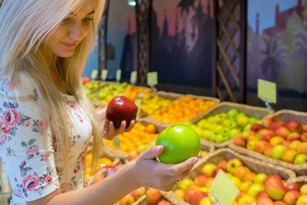 Девушка в продуктовом выбирает яблоки Стоковое Изображение
