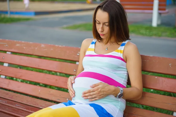 Mujer embarazada sentada en un banco — Foto de Stock