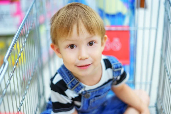 Αγόρι κάθεται σε ένα καλάθι του σούπερ μάρκετ — Φωτογραφία Αρχείου