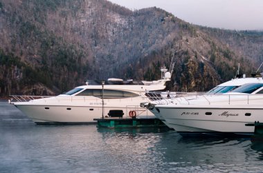 Beyaz tekne ve yatlar, dağların ve ormanların arka planına karşı körfezdeki tekne istasyonunda park halinde. Baraj gölünün üzerinde sis var. - Rusya. Krasnoyarsk. 19 Ekim 2019
