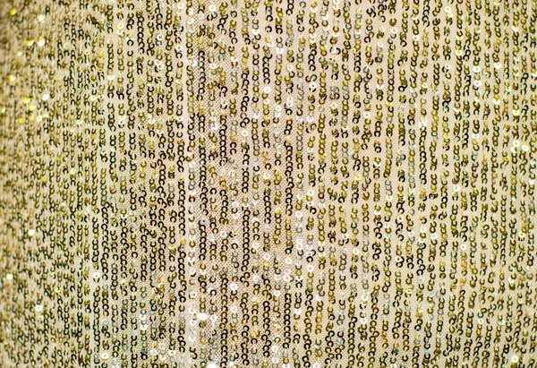 Gold fabric with round sequins. Elegant holiday background in gold color. Scaly pattern.