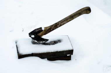 Beyaz karın arka planına odun kesmek için hazırlanmış bir balta. Ev işleri için araçlar.