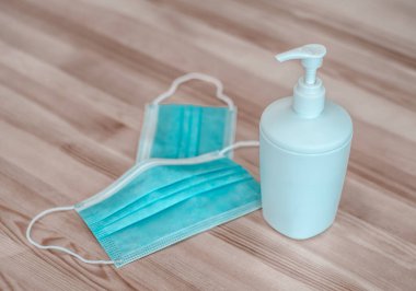 Coronavirus. Koruyucu yüz maskeleri ve bir şişe dezenfektan tahta yüzeyde duruyor. Savaşan salgın.