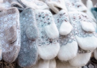 Farklı süslemeleri olan hafif tüylü ipliklerden örülmüş eldivenler sırada duruyor. Kış mevsimi için sıcak aksesuarlar.