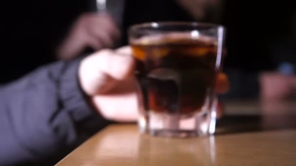 Whisky sobre mesa de madera y hombre con whisky en la mano — Vídeo de stock