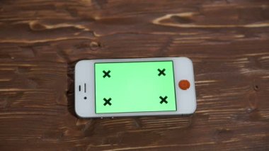 Ahşap masa yeşil ekran akıllı telefon.