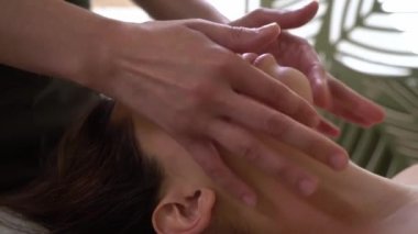 Spa yüz masajı. Kozmetik uzmanının ofisinde şekillendirilmiş yüz masajı işlemi. Güzel bir kadın görünüşüne özen gösterir. Güzellik uzmanı müşterisine masaj yapıyor, yaşlanma belirtilerini ortadan kaldırıyor.