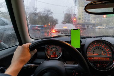 Araba gösterge panelindeki telefon tutacağına modern akıllı telefon aygıtı monte edilmiş. Yapay yeşil krom anahtar ekranı izole şablonu. Metin için kopyalanma alanı. Araç iç kokpit manzaralı. Traffi karıştırma bilgi uygulaması