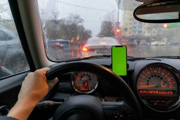 Modern smartphone device gadget mounted on phone holder at car dashboard. Mock-up green chroma key screen isolated template. Copyspace for text . Vehicle interior cockpit view. Traffi jam info app