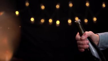 Şişeden köpüklü şampanya ağır çekimde akıyor. Elleri şampanya şişesini tutuyor. Mutlu yıllar konsepti