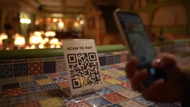 Femme scanne le code QR affiché par le marchand avec son téléphone pour payer le service dans le café. Paiements sans contact pendant la période de distanciation sociale. — Video