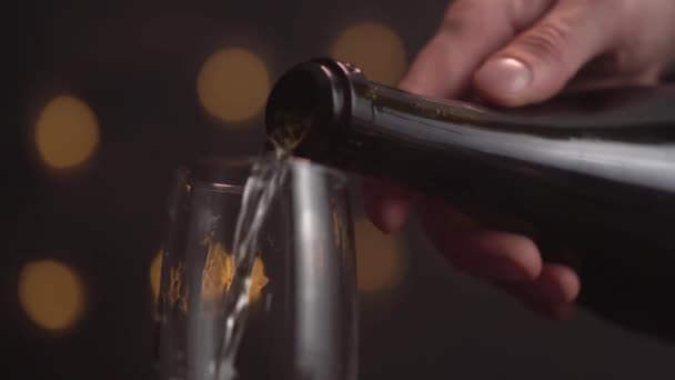 Zbliżenie barmana wlewając szampana do szklanki na czarnym tle, szklanka ma dużo piany i bąbelków. Sztuczne oświetlenie. Zwolniony ruch. — Wideo stockowe