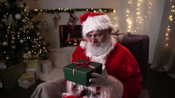 크리스마스 선물 상자가 있는 재밌는 산타 클로스 선물. 새해 선물을 고르는 일. 크리스마스 트리 밑에 산타가 설치되어 있다. 12 월 - 크리스마스 이브 이전. 신년 꿈의 성탄절 정신. — 비디오
