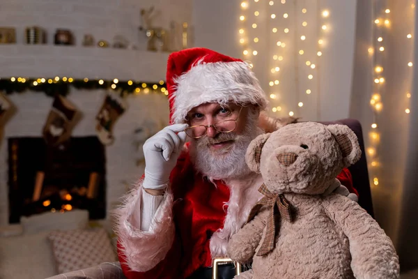 Śmieszny Mikołaj siedzi w swoim rocker roku choinka z misiem ducha Bożego Narodzenia, święta i uroczystości koncepcja — Zdjęcie stockowe