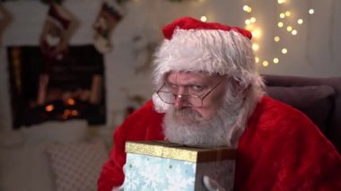 Açgözlü Noel Baba 'nın elinde bir kutu Noel hediyesi var. Yeni yıl hediyeleri seçiyorum. Noel Baba ağacın altında hediyeler dağıtıyor. Noel 'den önceki Aralık Akşamı. Yılbaşı hayali Noel konseri