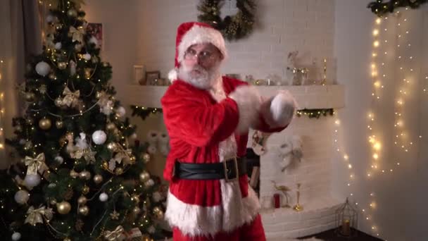 Retrato de Papá Noel moderno bailando en apartamento decorado cerca del árbol de Navidad con pelotas y luces. Celebraciones y concepto de personas alegres. — Vídeos de Stock