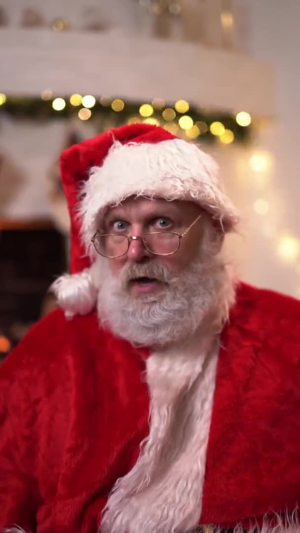 Retrato divertido Santa Claus en gafas sentadas en su rockero cerca del árbol de Navidad. Espíritu navideño, vacaciones y concepto de celebraciones. Vídeo vertical — Vídeo de stock